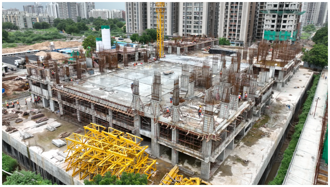 Wide exterior shot of a Skrutim Infra construction site showing scaffolding and structural framework